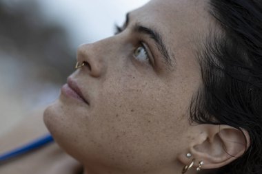 Profilde genç bir kadının yüzü yukarı bakıyor, düşünce ve düşüncelere dalmış.