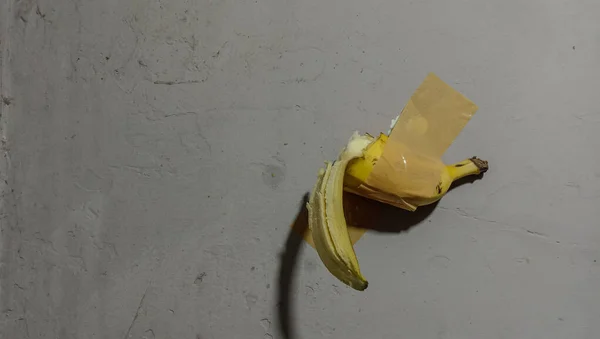 Yarım muz şeffaf kahverengi yapıştırıcı kullanarak duvara yapışmış..