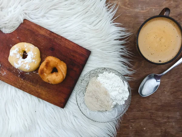 Kesme tahtasında pişmiş çiğ çörekler, malzemeleri ve masada bir fincan beyaz kahve, yiyecek ve içecek teması..