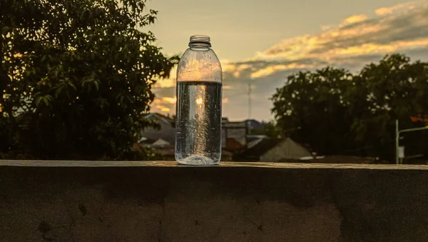 Beton bir çitte suyla dolu şişeler ve parlak bir erken sabah atmosferi, geri dönüşümlü sürdürülebilirlik teması