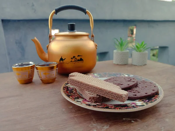 Kurabiyeler ve çikolatalı gofretler bir tabakta 2 bardak çay hepsi etkinlik, yemek ve içki teması için masada..