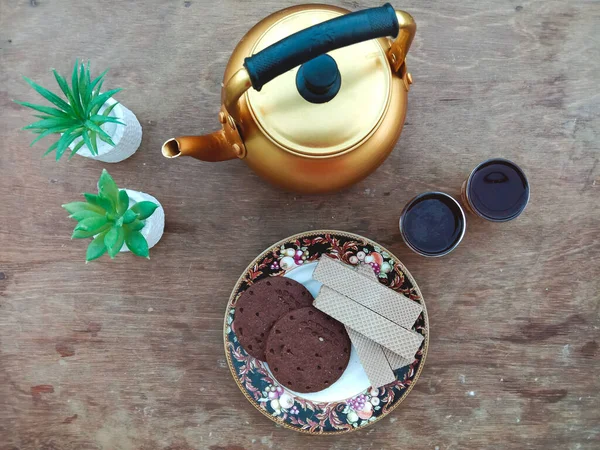 Bir tabak çikolatalı abur cubur ve iki fincan çayla dolu bir masanın üst görüntüsü..