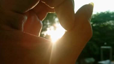 Bir el siluetinin yatay yakın çekimi, güneş doğarken güneşi yakalamak için bir işaret oluşturuyor. Yeni bir başlangıç, sabah ilhamı, başarı ve doğada pozitif enerji kavramı.