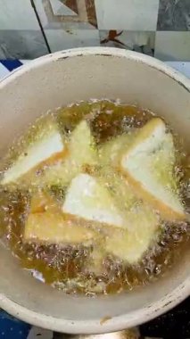 Yüksek açılı tofu parçalarının kaynayan sıcak yağlı tavada kızartıldığı bir kare yakın çekim. Özgün ev yemekleri, geleneksel Asya yemekleri hazırlama, dikey yönelim.