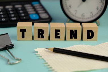 Bir yönetim ve pazarlama konsepti olarak dizüstü bilgisayarın, hesap makinesinin ve gözlüklerin yanına yeni trendlerin yazıldığı bir tahta blok. 