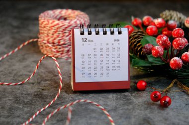 Aralık 2026 için aylık masa takvimi Noel süsleri temasının yanındaki ahşap masada.