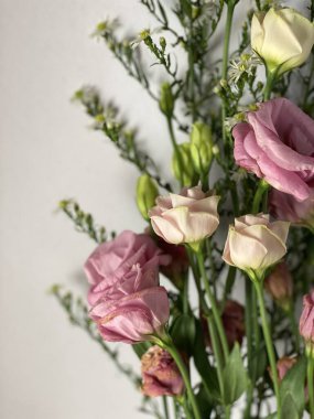 Üzerinde pembe karanfil çiçekleri, pastel not defteri ve kısmen görünür pembe bardak seti olan pembe ve yeşil temalı bir fotoğraf. Mesajınız, aşk, yumuşak, kadınsı ve romantik konsept.