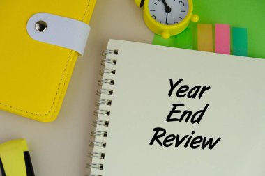 Alarm saati, kalem ve Yıl Sonu İncelemesi ile yeşil arkaplan üzerine yazılmış notların seçici odak noktası.