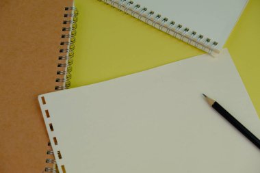 Sarı zemin üzerinde siyah kalem olan boş spiral bir defter aç. Metnin için Boş Alan. işletme ve eğitim kavramı