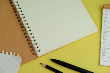 Sarı zemin üzerinde siyah kalem olan boş spiral bir defter aç. Metnin için Boş Alan. işletme ve eğitim kavramı