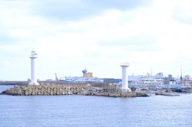 Jeju, Güney Kore - 11 Şubat 2026: Gün batımındaki Jeju cazibesi. Deniz feneri yakındaki beton kuleler