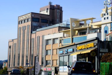 Jeju, Güney Kore - 11 Şubat 2026: Gün batımındaki Jeju cazibesi. Kıyıya yakın beton kuleler yel değirmeni