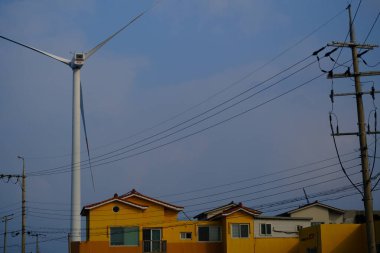 Jeju, Güney Kore - 11 Şubat 2026: Gün batımındaki Jeju cazibesi. Kıyıya yakın beton kuleler yel değirmeni