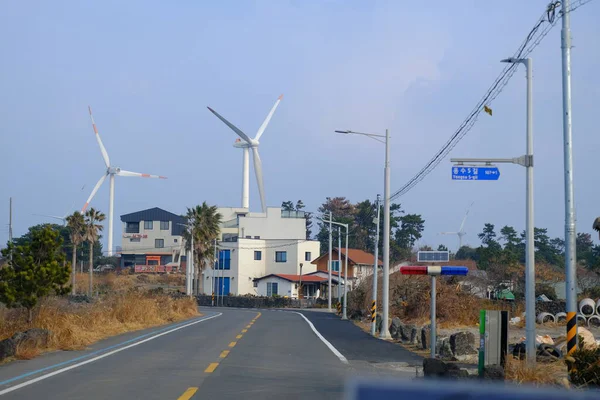 Jeju, Güney Kore - 11 Şubat 2026: Gün batımındaki Jeju cazibesi. Kıyıya yakın beton kuleler yel değirmeni