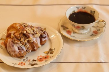 Geleneksel Polonya Aziz Martins kruvasanı (rogal witomarciski) arka planda bir fincan kahveyle klasik porselenler üzerinde servis edilir.. 