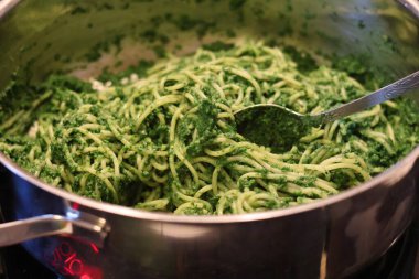 Makarnayı ıspanak, fesleğen, yeşil bezelye ve yeşil maydanozdan pesto ile hazırlama süreci: makarna ile pesto 'yu tencerede birleştirme.