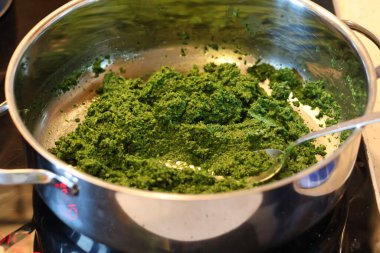 Ispanak, fesleğen, yeşil bezelye ve yeşil maydanozdan pesto ile makarna hazırlama süreci: zeytinyağı ve sarımsak ile karıştırılmış yaprakların görüntüsü