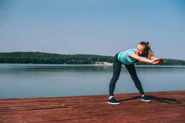 Vrouw voert oefeningen op pier — Stockfoto