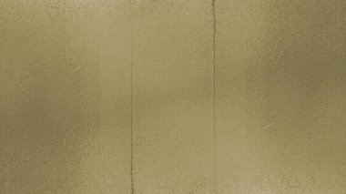 Kalıplı altın pirinç bir yüzeye yakın çekim, sıcak, metalik bir parıltı sergiliyor. Yüzey bütünü boyunca ince, tanecikli bir dokuya sahiptir, hafif noktalı veya mat bir görünüm oluşturur..