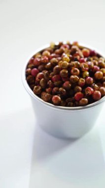 Çin mutfağında aromatik baharat olarak kullanılan beyaz arka planda metalik bir kasede sichuan biberlerini yakından çek..