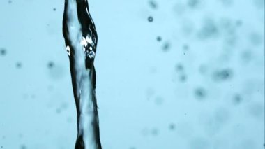 Açık mavi arkaplan üzerine dökülen ve şiddetle sıçrayan temiz su akıntısı kabarcıklar ve kaotik sıvı hareketler yaratır.