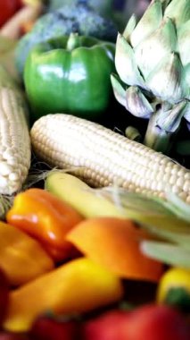 Koyu bir yüzeye dizilmiş mısır, biber ve brokoli de dahil olmak üzere taze ve sağlıklı sebzelerden oluşan renkli bir çeşitliliğin aşağı eğimli görüntüsü..