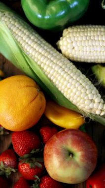 Eğik çekim, ahşap bir masada renklerine göre sıralanmış taze, sağlıklı meyve ve sebzelerin rengarenk çeşitlerini gözler önüne serer..