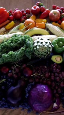 Renkli, taze, sağlıklı meyve ve sebzelerin gökkuşağı etkisi yaratmak için ahşap bir masa üzerindeki renklerine göre sıralandığı geniş bir çeşitliliğin baştan aşağı görsel çekiciliği..