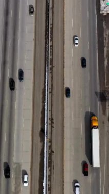 Çok yönlü bir otoyolun yüksek açılı görüntüsü. Karla kaplı bir arazide ilerleyen ve büyük bir kavşağa ve karla kaplı tepelere dönüşen ılıman bir trafik var..