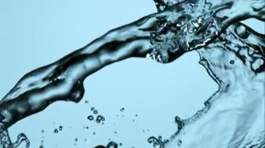 Temiz suyun yüksek hızda çekilmesi havada sıçrayıp dans etmesi açık mavi bir zemin üzerinde karmaşık sıvı şekiller ve damlacıklar oluşturur.