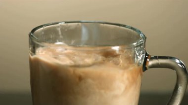 Taze sütün bir bardak koyu kahvenin içine dökülmesi çok güzel kahverengi ve beyaz kıvrımlar ve kabarcıklar yaratır.