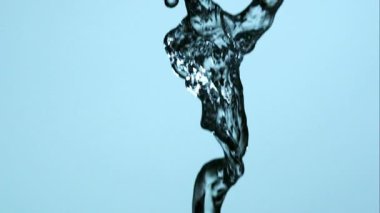 Dikey temiz su akıntısı, mavi arka plana doğru yavaş çekimde uçan damlacıklar ile büyük bir sıçramaya neden oluyor.