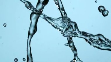 Kristal berraklığında su sıçrıyor ve yüksek hızda ağır çekimde dönüyor açık mavi bir arka plana karşı güzel sıvı şekiller ve damlacıklar yaratıyor.