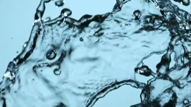 Yüksek hızlı yavaş çekim kristal berrak su sıçrayan ve havada çarpışan katı mavi stüdyo arka planı