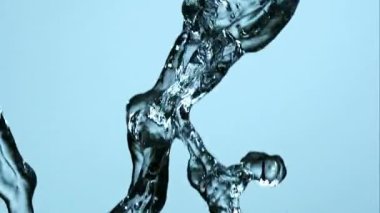 Temiz su akıntılarının dinamik yavaş çekim görüntüsü bir stüdyo ortamında açık mavi bir arkaplan ile karışıp sıçrıyor.