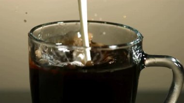 Taze beyaz süt akıntısı, cam bardağa dökülen koyu siyah kahve güzel kıvrımlı dokular ve krema bulutları yaratır.