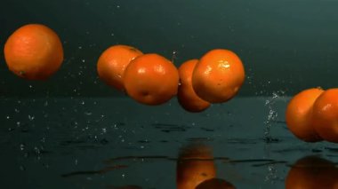 Birkaç Taze Portakal Sulama ve Dramatik Stüdyo Aydınlatma ile Karanlık Yansıtıcı Yüzeyde Yavaş Çekimde Düşüyor ve Zıplıyor