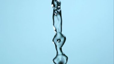 Kristal berrak suyun sürekli akışı açık mavi bir stüdyonun arka planına karşı büyük kabarcıklar ve damlacıklar oluşturur.