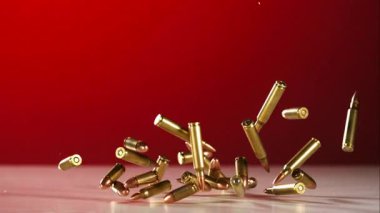 Yüksek Hız Yavaş Çekimde Kırmızı Arkaplan 'a karşı Beyaz bir zeminde Düşen ve Zıplayan Çoklu Pirinç Tüfek Mermileri