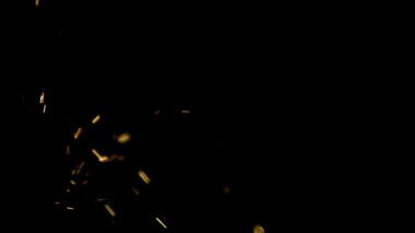 Parlak altın kıvılcımlar ve parlayan közler ağır çekimde koyu siyah bir arka plana karşı ekranda yatay olarak uçuyor.