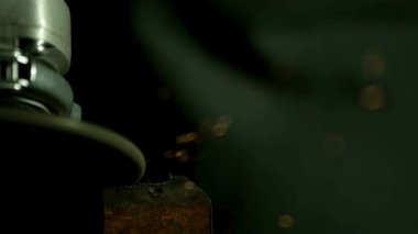 Parlak turuncu kıvılcımlar üretirken paslı bir metal parçasını kesen endüstriyel açı öğütücüsünün detaylı görüntüsü