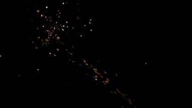 Parlak altın kıvılcımlar ve parlak közler havada zifiri karanlık zemine doğru uçuyor stüdyoda dramatik bir endüstriyel ya da kutlama görüntüsü yaratıyor.