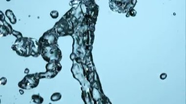 Dinamik yavaş çekim, temiz şeffaf suyun sıçraması ve güzel sıvı damlacıklar oluşturması parlak açık mavi bir stüdyo arka planına karşı dalgalanmalar