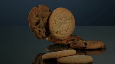 Çeşit çeşit çikolatalı ve şekerli kurabiyeler yavaş çekimde koyu renkli bir stüdyo masasına düşüp çıkıyordu.