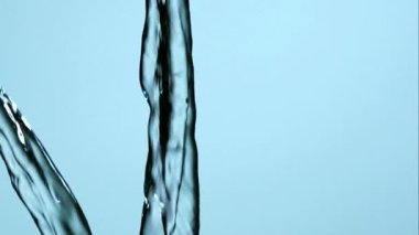 Temiz temiz temiz su dökülüyor ve yüksek hızlı makro çekim karşısındaki parlak mavi arka plan sağlık ve hidrasyon konsepti video görüntüleri yavaş çekim stüdyo ışıklandırması