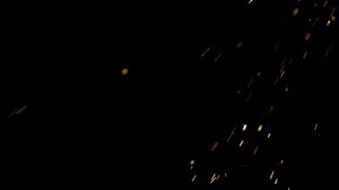 Parlak turuncu parlak kıvılcımlar yavaş çekimde karanlık bir arkaplanda uçuşuyor ve ısı ve endüstriyel enerjinin dramatik bir etkisine yol açıyor.