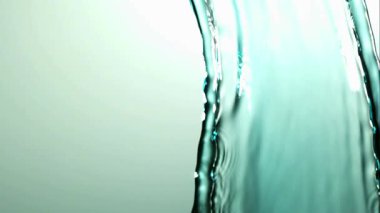 Yumuşak, açık yeşil bir zemine, temiz akıntıda oluşan soyut dalgalanmalar ve kabarcıklarla ağır çekimde akan berrak sıvı su.