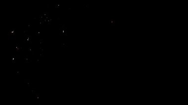 Küçük gümüş ve beyaz kıvılcımlar ve közler, yaratıcı bir video kaplaması için ince ve zarif bir hareketle koyu siyah bir arkaplana karşı dikey düşüyorlar.