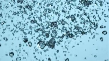 Kristal berrak su damlacıkları ve akarsular havada dikey olarak soluk mavi bir zemin üzerine düşerek ferahlatıcı ve temiz bir sıvı doku oluşturur.