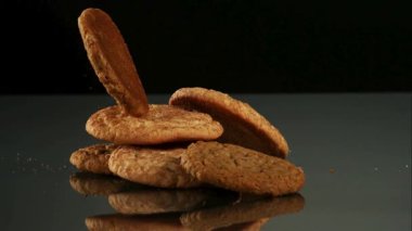 Taze pişmiş zencefilli kurabiyeler ve yulaflı kurabiyeler koyu renkli bir yansıtıcı yüzeyin üzerine düşer ve bisküvilerin üzerine düşer.